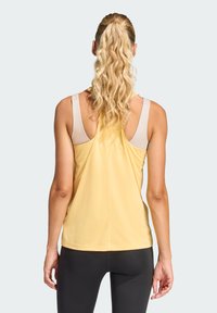 Camiseta deportiva sin mangas amarilla con un corte relajado, que presenta una textura suave y tirantes claros contrastantes, diseñada para ropa activa.