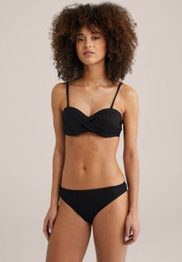 Fekete bikini textúrált anyaggal, csavart elülső kialakítással, vékony állítható pántokkal és egy hozzáillő, alacsony derekú alsórésszel.