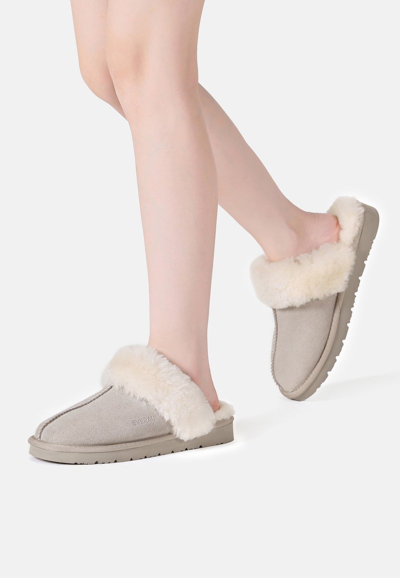 Gray suede slippers with a cream faux fur lining, slip-on design, and textured rubber sole, showcasing soft materials and a cozy appearance.