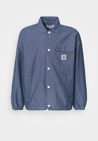 Denim jacket in dark blue with a button-down front, chest pocket, elastic cuffs, drawstring hem, and Carhartt logo patch on the pocket.