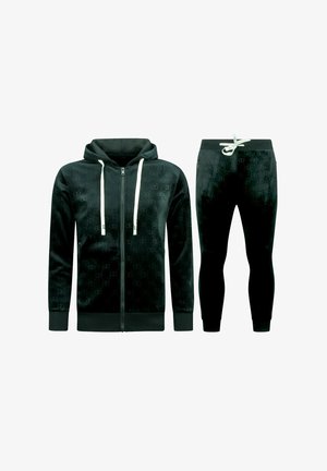 Zwart velours trainingspak met een capuchon met volledige rits en witte trekkoorden, en bijpassende joggingbroek met witte taillebandstrik.