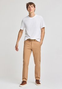 Vit bomull t-shirt, khaki bomullsbyxor, bruna sneakers med vita sulor, beige vävt bälte. Enkelt mönster, avkopplad passform, inga mönster.