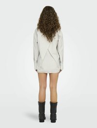 Robe chemise rayée avec un design croisé au dos, manches longues et ourlet élastique. Portée avec des bottes noires jusqu'aux genoux.