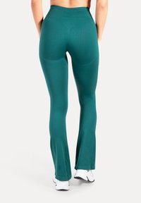 Türkisfarbene, ausgestellte Leggings aus elastischem Stoff mit hohem Bund, glatter Oberfläche und figurbetontem Schnitt für mehr Bewegungsfreiheit.