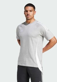 Grijze sportieve t-shirt van zachte stof, met witte zijaccenten en drie witte strepen op de schouders. Ronde halslijn, ontspannen pasvorm.