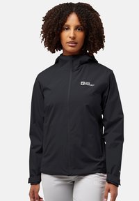 Giacca nera impermeabile con collo alto, zipper completa e logo sul lato sinistro del petto. Presenta maniche lunghe e polsini regolabili.