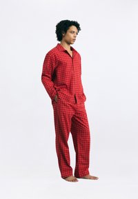 Red checked pajama set made of soft fabric, featuring a button-down shirt and loose-fitting pants with an elastic waistband.