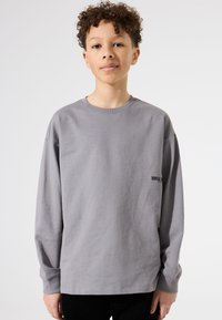 Grijze katoenen t-shirt met lange mouwen en een ronde hals, met een kleine zwarte "TOTAL" print op de linker borst. Glad textuur.