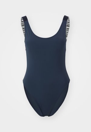 Navy blue one-piece swimsuit with wide straps featuring a contrasting graphic pattern. Smooth texture, scoop neck, and moderate leg cut.