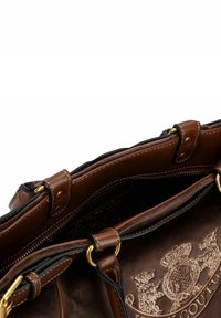 Borsa in pelle marrone con ferramenta dorata, un compartimento con cerniera e un emblema ricamato che presenta uno scudo coronato e testo all'interno in suede.