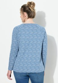 Camiseta de manga larga azul con un patrón de olas, que cuenta con un cuello redondo y mangas raglán. Hecha de una tela suave con un corte relajado.