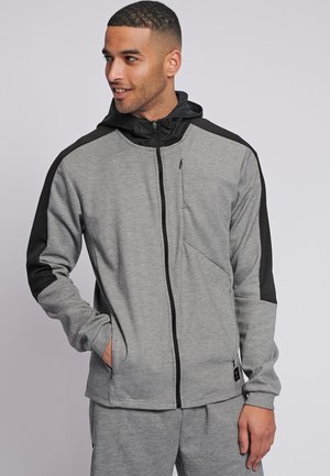 Grijze zip-up hoodie met zwarte schouderaccenten. Heeft een hoge kraag, lange mouwen en twee zijzakken. Gemaakt van een zachte, gestructureerde stof.