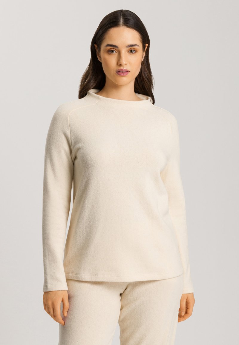 Cremefarbenes Langarmshirt aus weichem Stoff mit lockerer Passform und rundem Halsausschnitt. Einfache und glatte Textur.