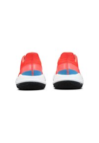 Baskets de sport rouges avec un dessus sans couture, semelle intermédiaire blanche, semelle extérieure noire et accents bleus sur le talon et les panneaux latéraux.