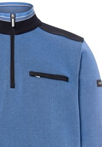 Pullover a mezza zip in tessuto a costine di un azzurro chiaro con dettagli neri. Presenta una tasca sul petto con zip e un design del colletto strutturato.