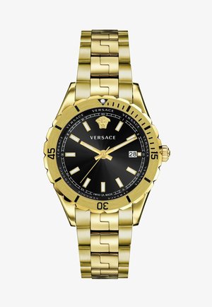 Versace gold-tone watch with a black dial, luminous hour markers, date display, and linked band featuring a polished finish and rugged bezel.
