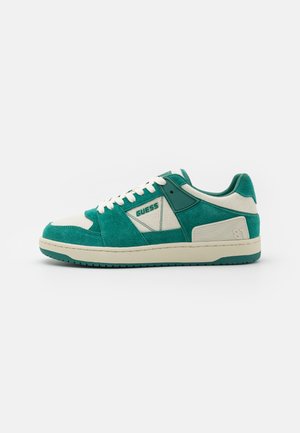 Sneaker verde in suede con accenti crema, dotate di una tomaia texture, lacci piatti e suola in gomma. Logo 'GUESS' sul lato.