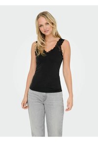 Zwarte tanktop met kantdetails langs de halslijn en schouderbanden. Zachte stof, slim fit ontwerp, gecombineerd met lichtgrijze denimjeans.