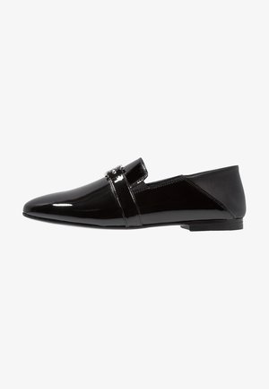 Svarta loafers i lackläder med spetsig tå och en dekorativ rem över vristen. Mjukt ytskikt och låg, platt sula.