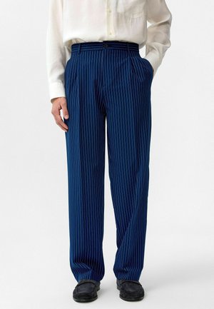 Marineblauwe gestreepte broek met een relaxte pasvorm, voorzien van een knoopsluiting en zijzakken. Het materiaal lijkt soepel en lichtgewicht.