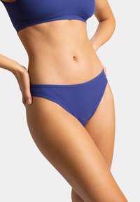 Bas de bikini violet à côtes avec un design taille basse. Texture lisse et couverture minimale, avec une finition à bords nets.