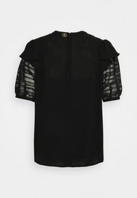 Blouse noire avec manches courtes bouffantes en dentelle, col rond et fermeture éclair au dos ornée d'un accent doré.