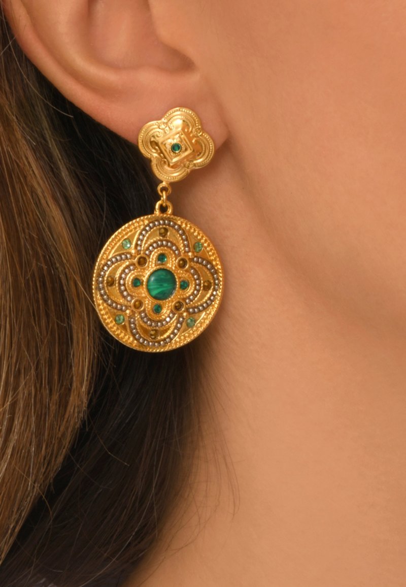 Boucles d'oreilles dorées avec un design floral, ornées de pierres vertes et d'un travail du métal complexe ; partie inférieure circulaire avec un attachement décoratif en haut.