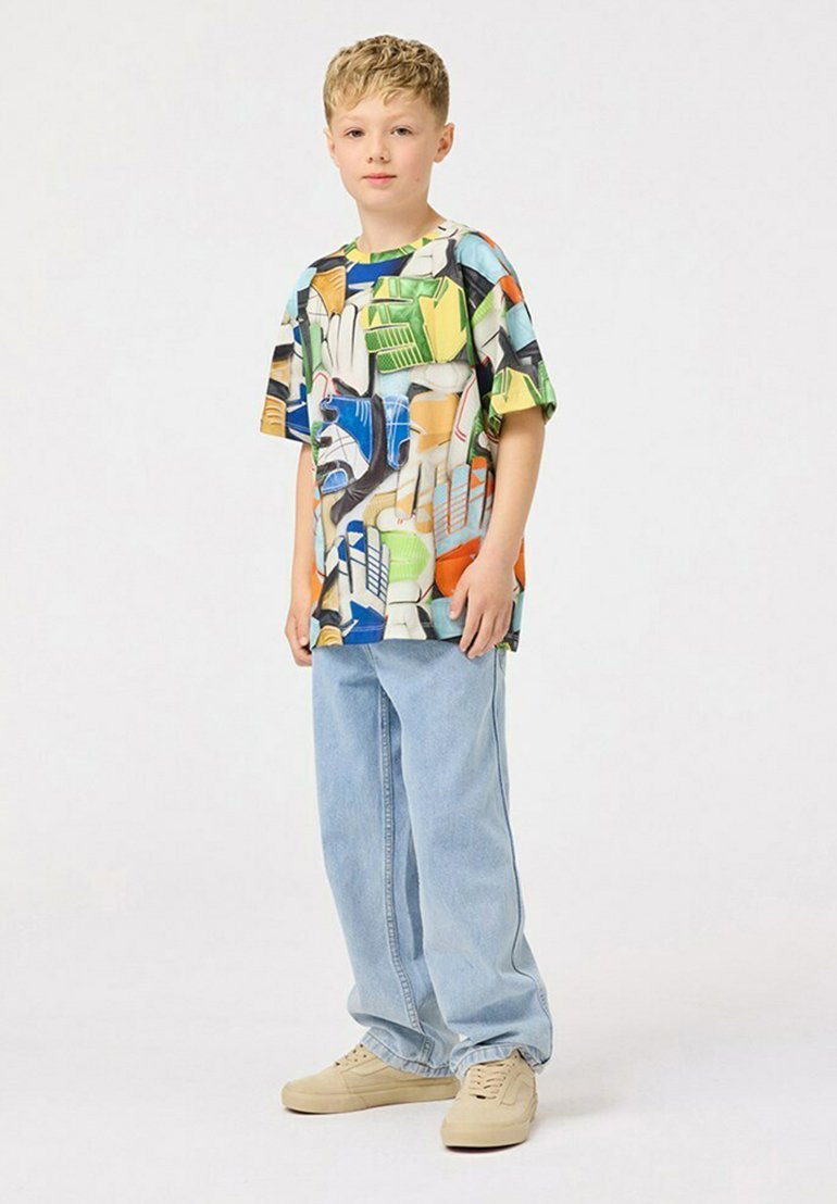 Lyhythihainen, monivärinen paita, jossa on abstrakteja kuvioita, yhdistettynä vaaleansinisiin, väljään mallisiin farkkuihin ja vaaleanruskeisiin tennareihin. Yksinkertainen ja rento muotoilu.