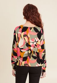 Kleurvolle gebreide trui met een patroon van abstracte vormen in roze, groen, zwart en geel, met een ronde halslijn en een geribbelde zoom.