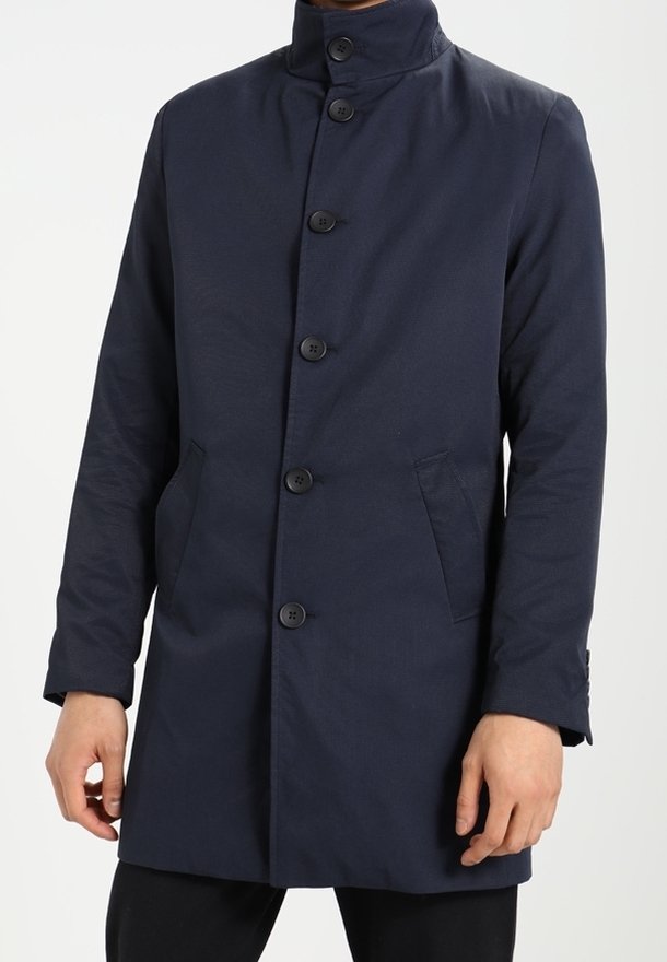 Cappotto blu navy con colletto alto, cinque bottoni frontali, due tasche laterali e tessuto testurizzato. Taglio aderente e maniche lunghe.