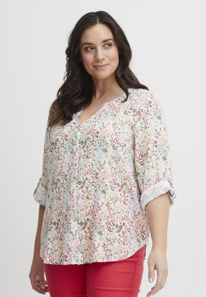 Blusa de tela ligera con estampado floral, que presenta flores de colores en rosa, azul y verde sobre un fondo blanco. Con botones y mangas remangadas.