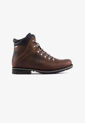 Hnědá kožená turistická bota s černým polstrovaným límcem, kovovým šněrovacím systémem a texturovanou gumovou podrážkou. Obsahuje logo na boku.