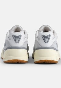 Białe i szare sneakersy z teksturowaną cholewką, amortyzowaną podeszwą oraz gumową podeszwą zewnętrzną. Zawierają akcent z logo na pięcie.