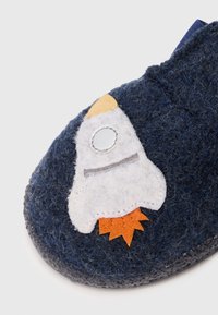 Zapatilla de casa de color marino con un diseño de cohete. Presenta acentos en blanco, gris y naranja. Forma redondeada con una superficie texturizada y suela plana.