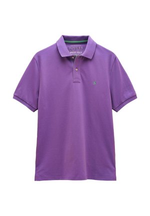 Fioletowa koszulka polo z krótkim rękawem, z dwoma guzikami przy kołnierzyku, zielonym logo na lewej piersi oraz klasycznym kołnierzem, ułożona płasko na białym tle.