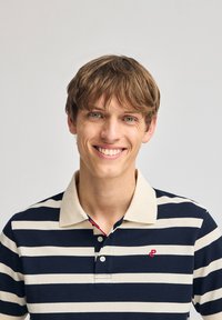 Marinblå och krämstripead polo skjorta med en beige krage, tre knappar och en liten röd logotyp på bröstet. Tillverkad av bomull.