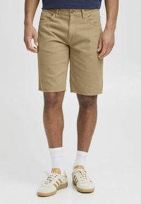 Khaki shorts lavet af bomuldsblanding. Har en lige skærm, bæltestropper og fem lommer. Bæres med en navy shirt og hvide sokker.