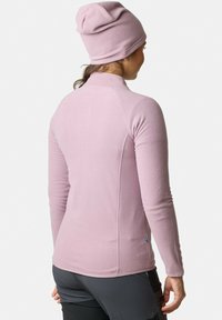 Top in pile rosa a maniche lunghe con colletto alto, dotato di una vestibilità attillata. Un berretto coordinato completa il look.