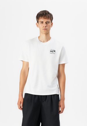 Cotton white t-shirt with a small black graphic on the left chest area, paired with loose black shorts. Simple crew neckline and short sleeves.