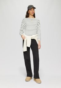 Ribakujulise valge ja musta triibuga särk, millele on paari pandud mustad püksid. Kremja sweatersoodiga, mis on seotud vöö ümber, ja beežid jalanõud viimistlevad komplekti.
