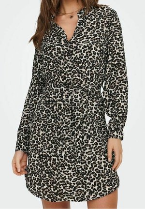 Vrouw draagt een lange mouwen, knielange jurk met luipaardprint, een V-hals en een bijpassende stoffen riem gestrikt in de taille.