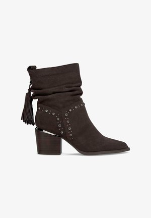 Stivaletto in suede marrone con gambale arricciato, nappina decorativa, accenti di borchie e tacco a blocco con effetto legno.