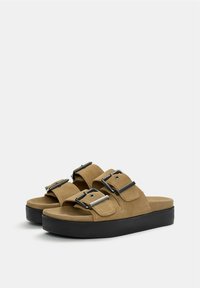 Tan suède platform sandalen met dubbele gespen en een zwarte rubberen zool, met een breed bandontwerp en een zachte textuur.