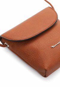 Hnědá kožená crossbody taška s texturovaným povrchem, klopovým uzávěrem a stříbrným logem. Kompaktní, obdélníkový tvar s tenkým popruhem.