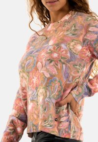 Pull en tricot multicolore à motif floral, présentant des textures douces, un col rond, des manches longues et une coupe décontractée, avec un petit logo en accent.