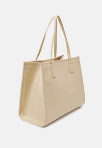 Beige draagtas gemaakt van glad synthetisch materiaal, met twee lange handvaten en een eenvoudig, gestructureerd ontwerp zonder zichtbare hardware of patronen.