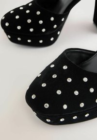 Juodos suede platformos kulniukai, papuošti toliau išdėstytais maži apvalūs sidabriniai taškai ant pirštų ir šonų.