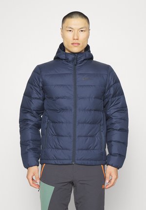 Marineblaue Wattierte Jacke mit Kapuze und Reißverschluss, mit gestepptem Textil und einem Logo auf der linken Brust. Strapazierfähiger Stoff mit elastischen Bündchen.