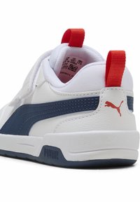 Chaussure de sport blanche avec des accents bleu marine, en cuir texturé, col rembourré, languette rouge au talon et détails du logo sur le talon.