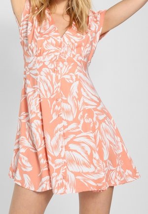 Kukkakuvioinen mekko pehmeää persikankaltaista kangasta, jossa on väljä istuvuus, lyhyet hihat, V-pääntie ja valkoiset kasvikuvioinnit nappidetaljeilla.